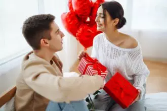 Young couple at home celebrating Valentines Day. Exchange of gifts. Surprise and love concept.